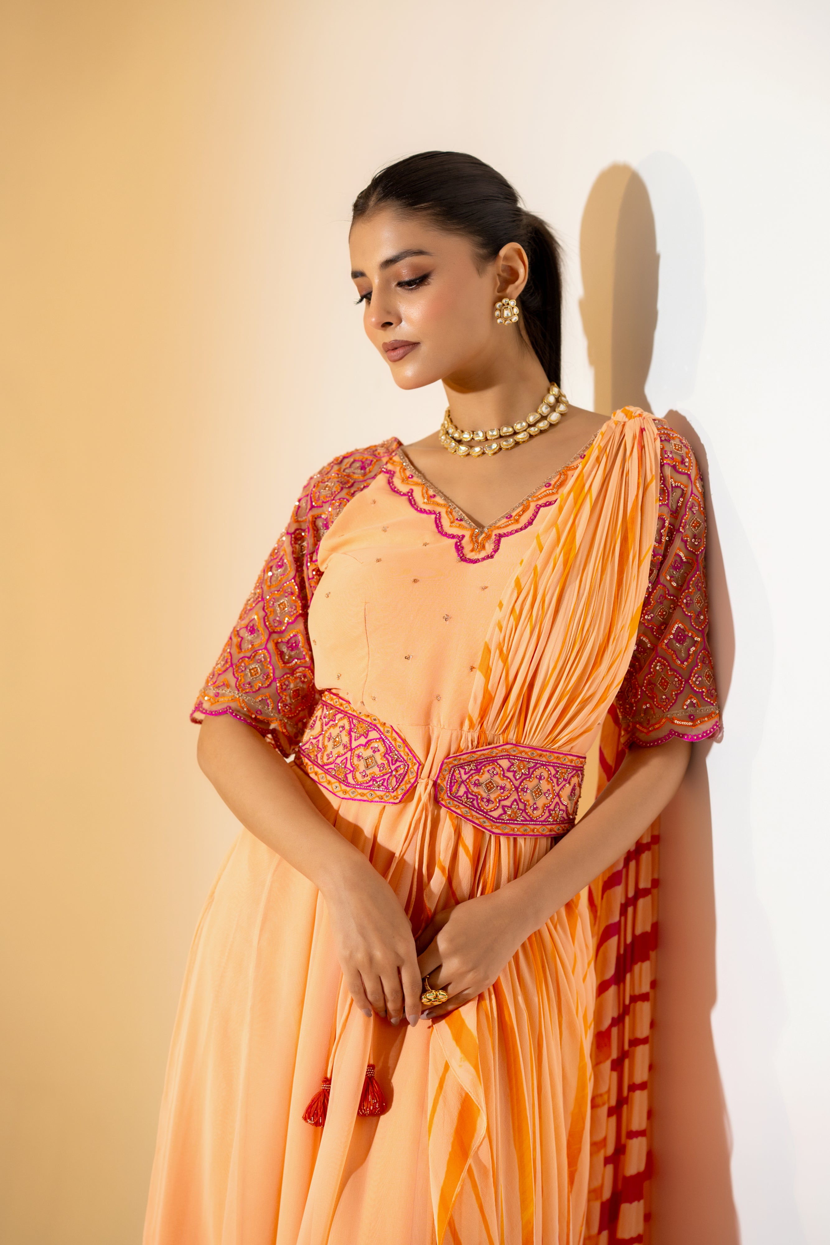 PEACH LEHERIYA DRAPED SAREE WITH EMBROIDERED NET SLEEVES & BELT.