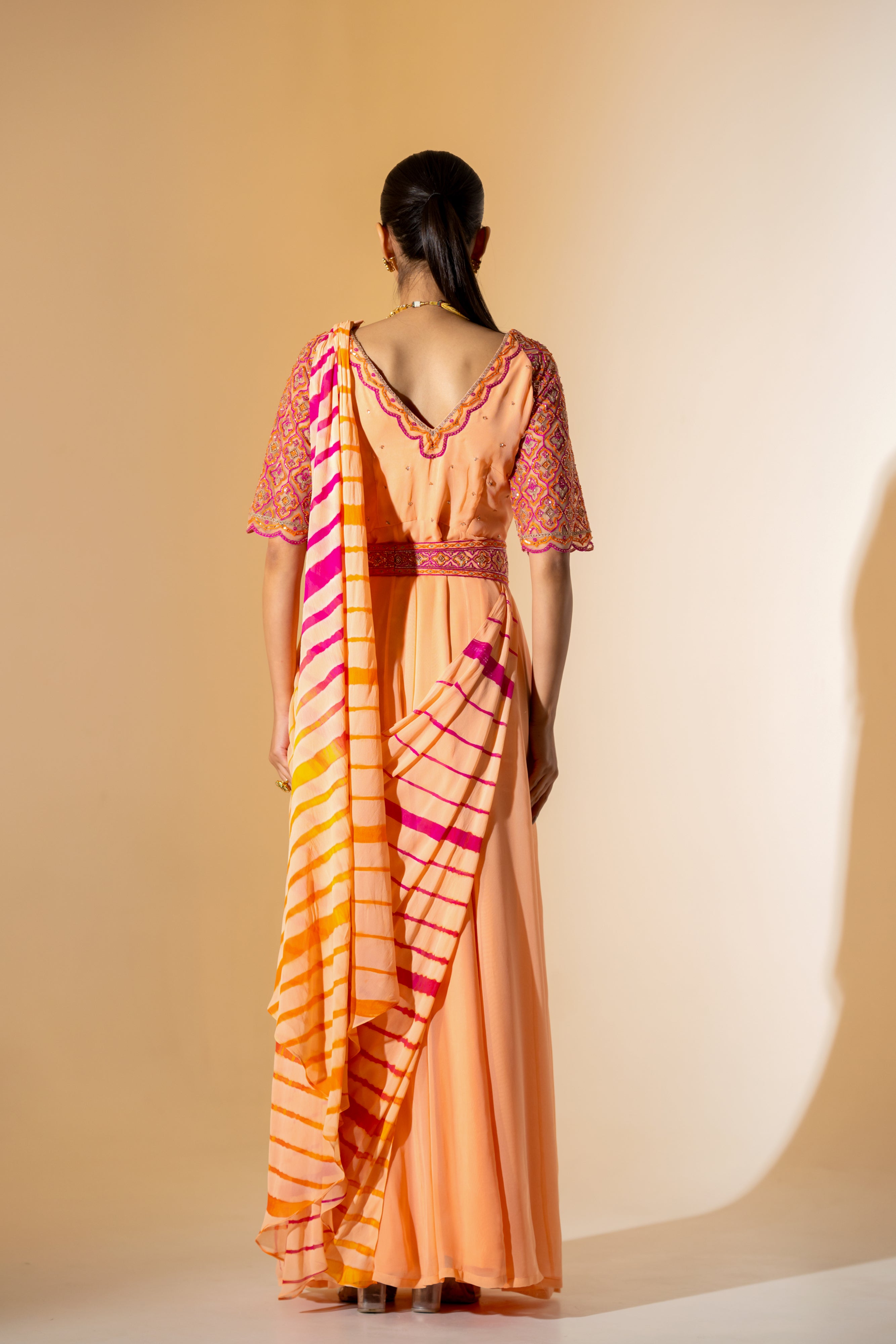 PEACH LEHERIYA DRAPED SAREE WITH EMBROIDERED NET SLEEVES & BELT.
