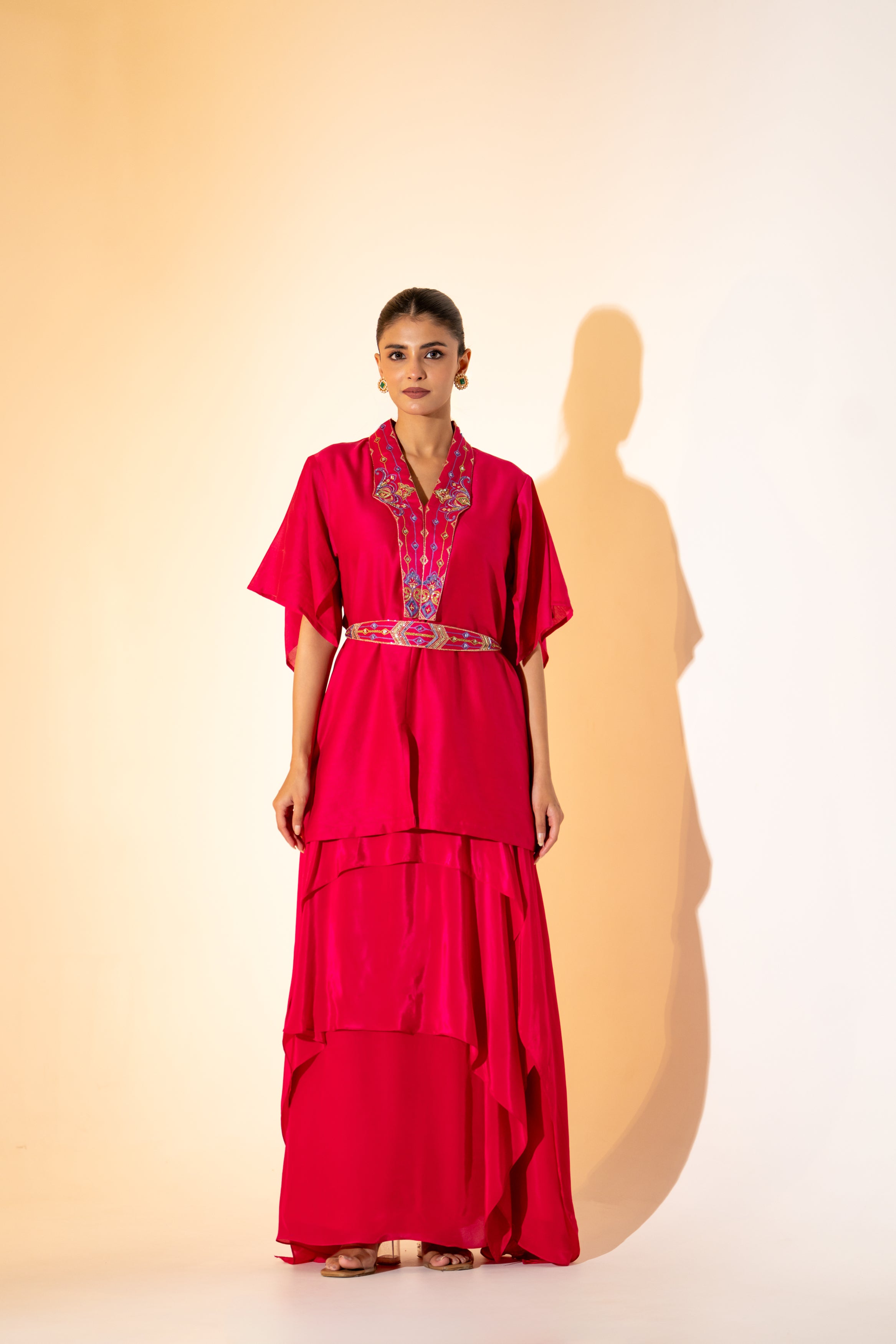 VIBRANT FUCHSIA TOP WITH EMBROIDERED NECKLINE AND BELT PAIRED WITH LAYERED SKIRT.
