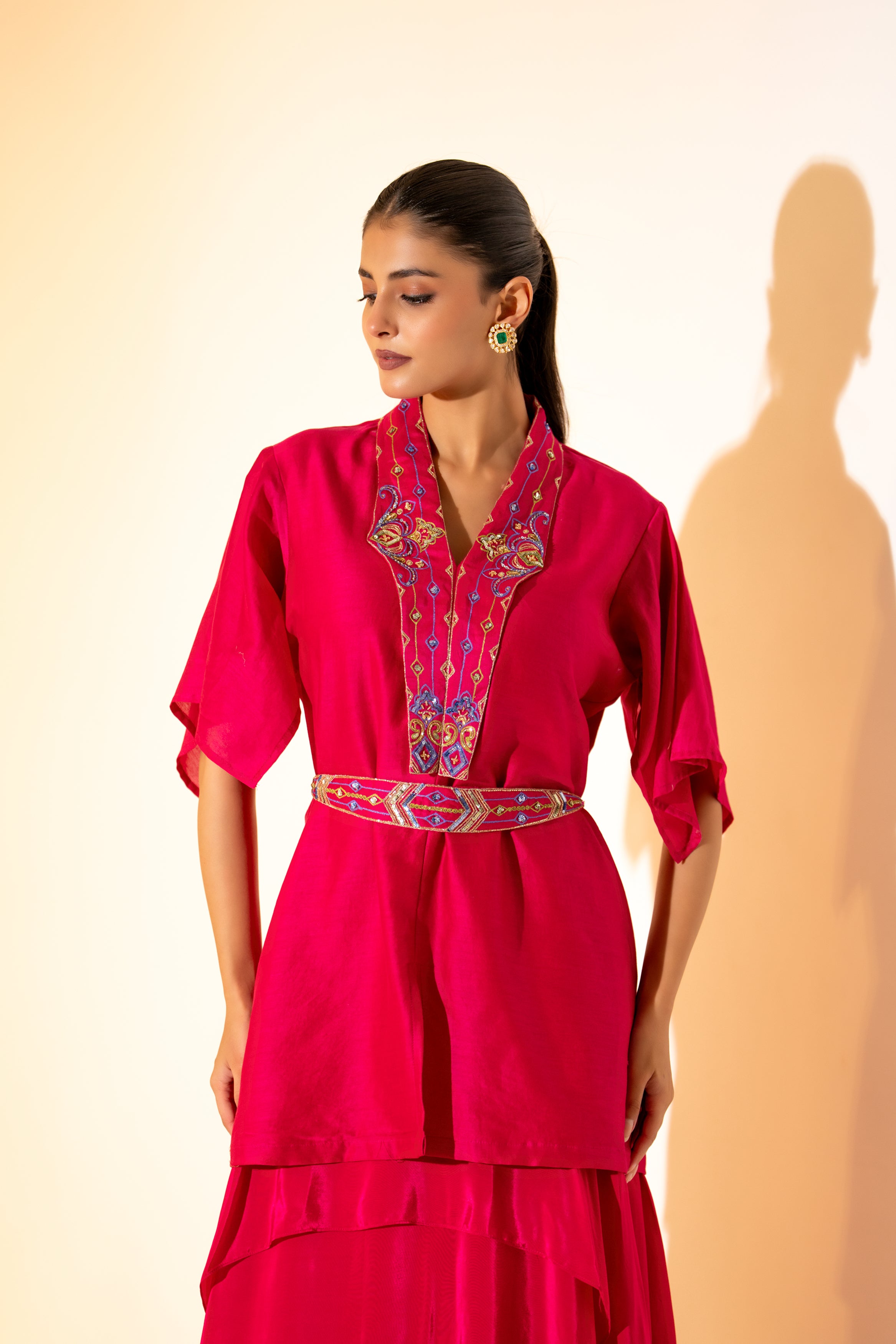 VIBRANT FUCHSIA TOP WITH EMBROIDERED NECKLINE AND BELT PAIRED WITH LAYERED SKIRT.