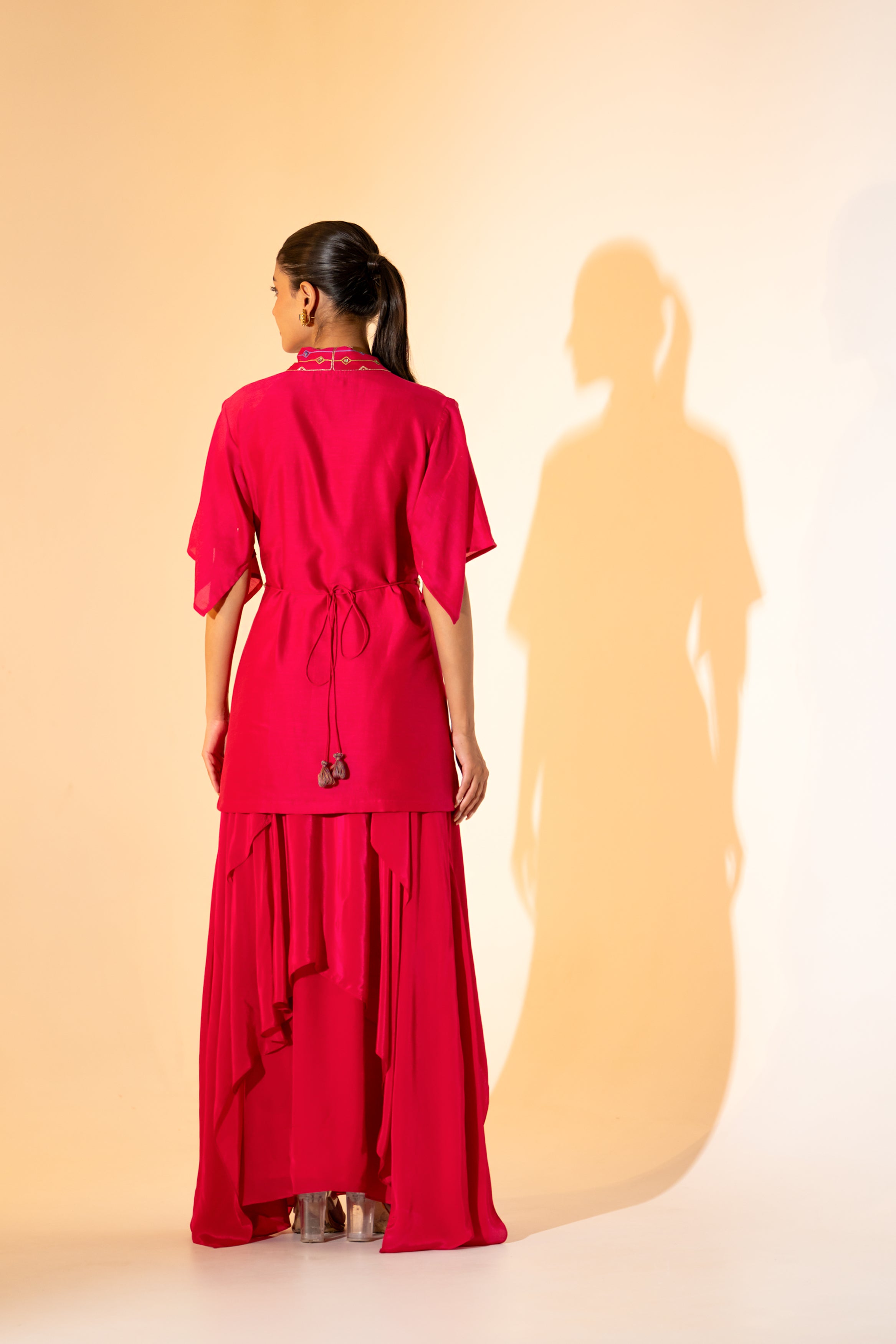 VIBRANT FUCHSIA TOP WITH EMBROIDERED NECKLINE AND BELT PAIRED WITH LAYERED SKIRT.