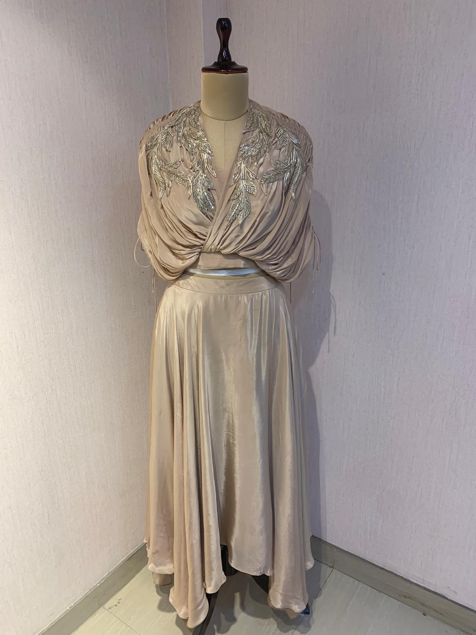 BEIGE BEAD AND WIRE EMBELLISHED CAPE TOP WITH DRAPED SKIRT.