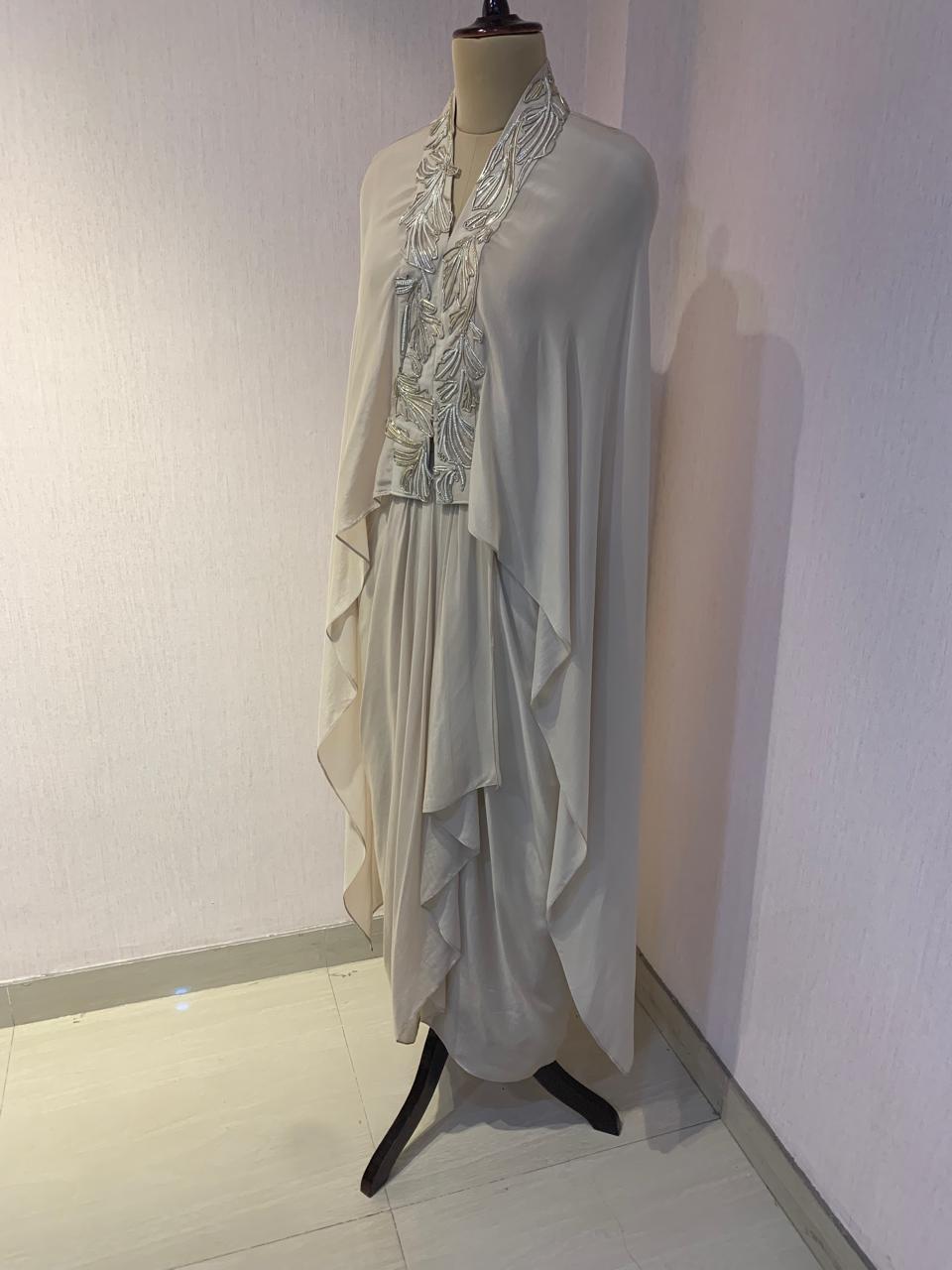 OFF WHITE EMBELLISHED CAPE WITH DRAPED SKIRT.