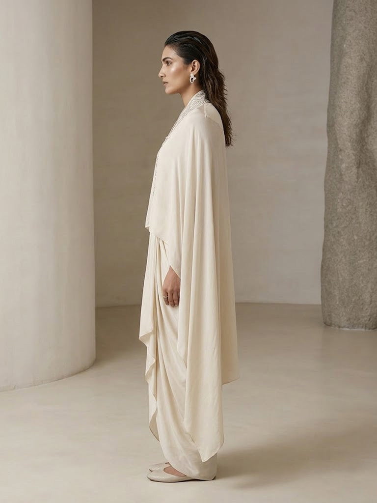 OFF WHITE EMBELLISHED CAPE WITH DRAPED SKIRT.